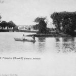 Curitiba - Postal em preto e branco que mostra uma canoa com duas pessoas no lago principal do Passeio Público, em 1904. Ao fundo, o engenho Bittencourt. Postal da Coleção Julia Wanderley. Acervo: Instituto Histórico e Geográfico do Paraná / Diretoria de Patrimônio Histórico, Artístico e Cultural / Fundação Cultural de Curitiba.